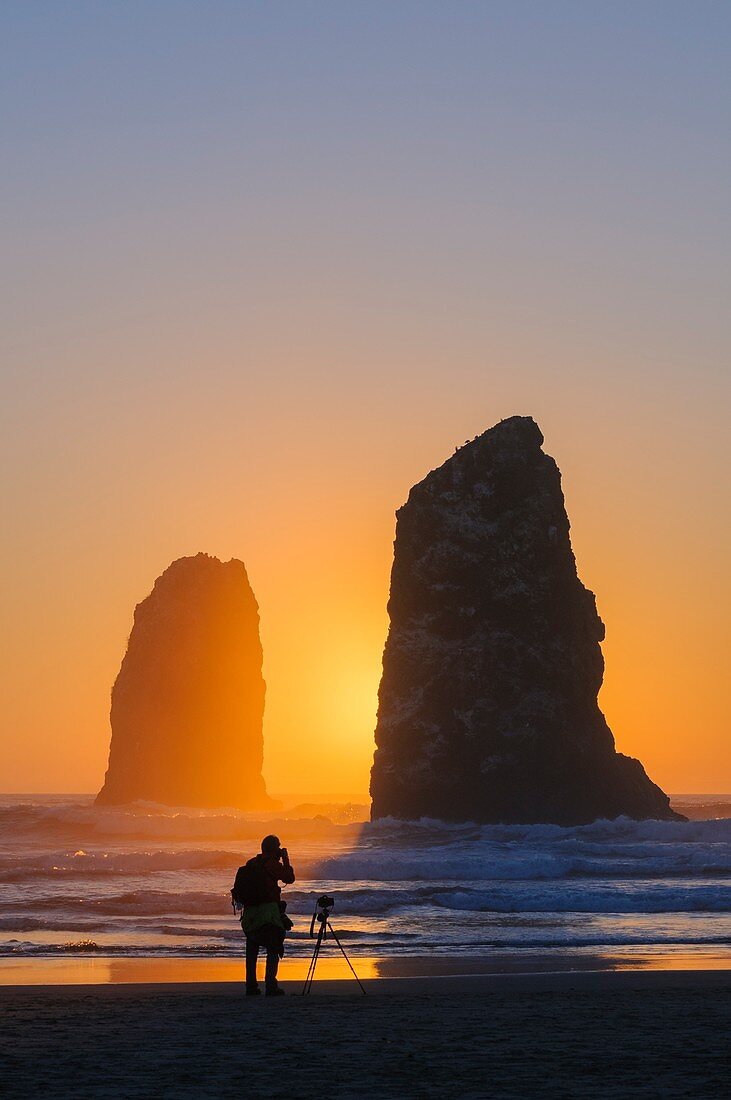 Mann, der die Nadeln am Haystack Rock in Cannon Beach an der Nordküste von Oregon fotografiert.