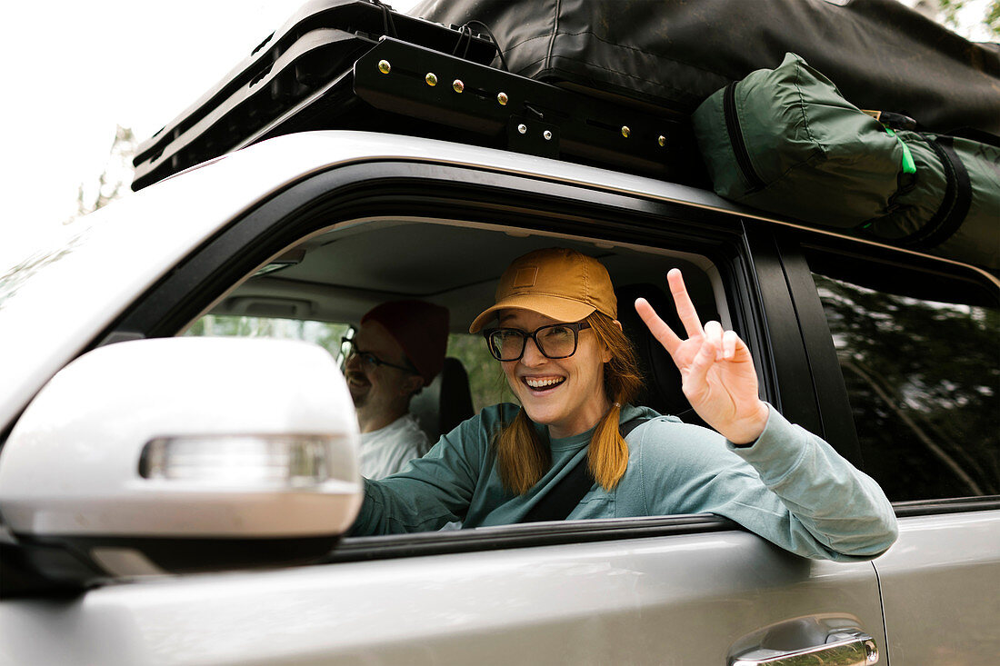 Woman and man sitting in off road car with tent on roof