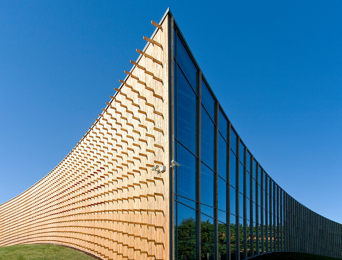 Modern university buildings, wooden beams projecting from a curved wood cladding wall, on a curved ground surface