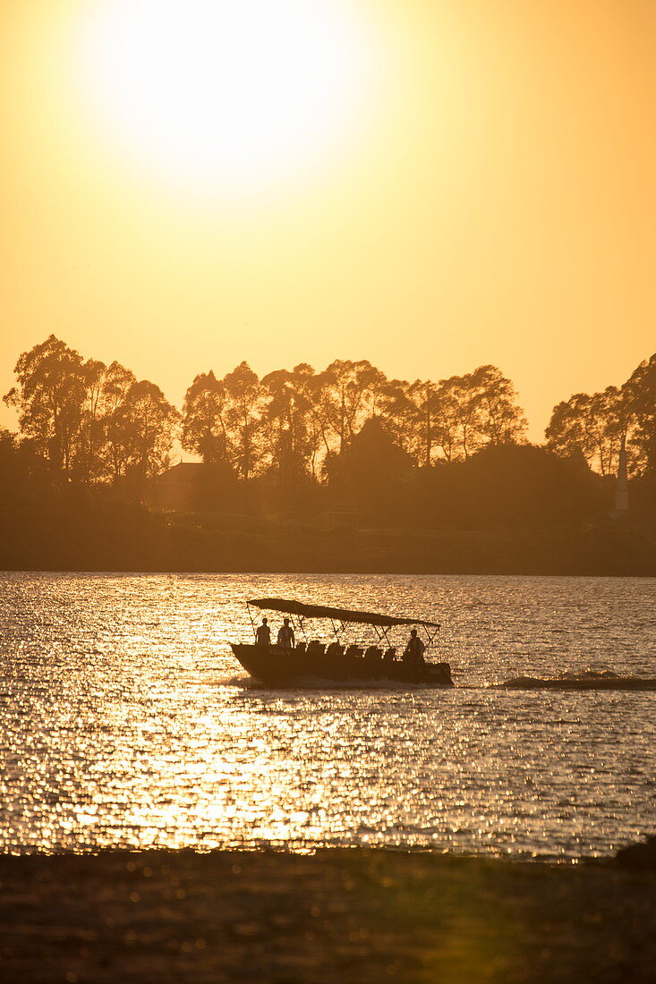 Silhouette of skiff dinghy from river cruise ship on the Mekong at sunset, near Preah Prosop, Mekong River, Kandal, Cambodia, Asia
