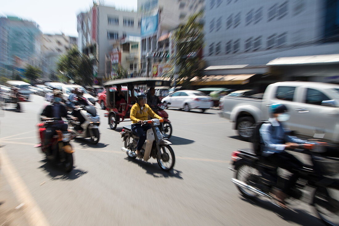 Zoomed image of people on mopeds and tuk-tuk on busy street, Phnom Penh, Cambodia, Asia