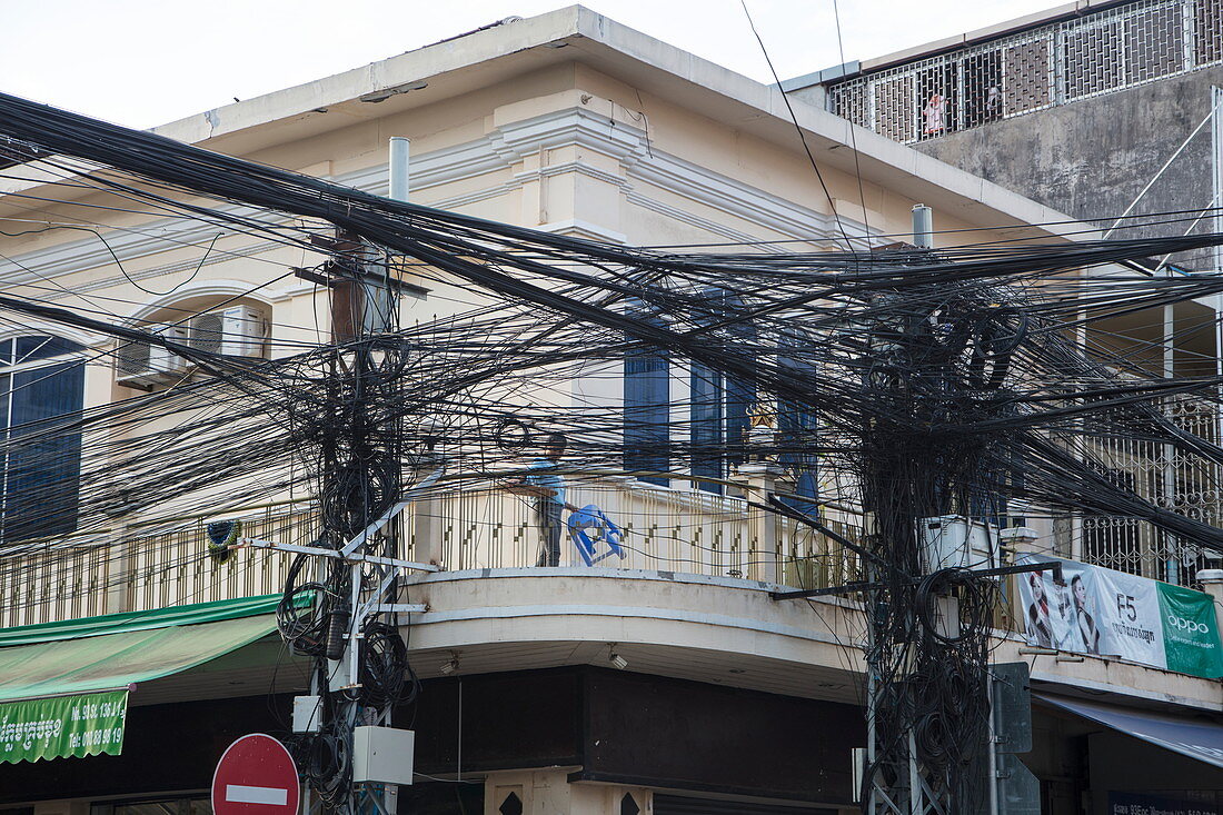 Eine chaotische und dennoch funktionierende Ansammlung an Strom- und Telefonleitungen in der Innenstadt, Phnom Penh, Kambodscha, Asien