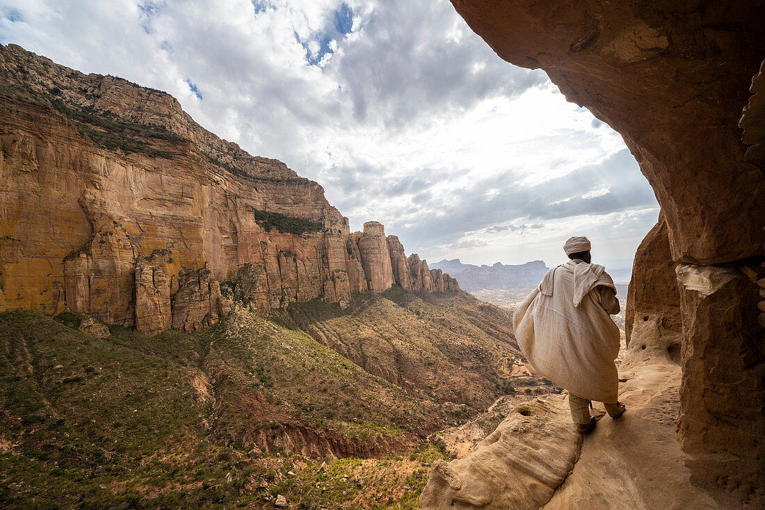 Rear view of priest walking on access trail to the rock-hewn Abuna Yemata Guh church, Gheralta Mountains, Tigray region, Ethiopia, Africa