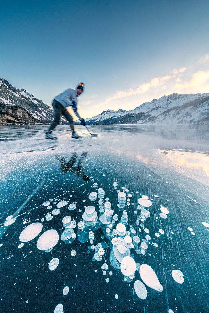 Man playing ice hockey on frozen Lake Sils, Engadine, canton of Graubunden, Switzerland, Europe