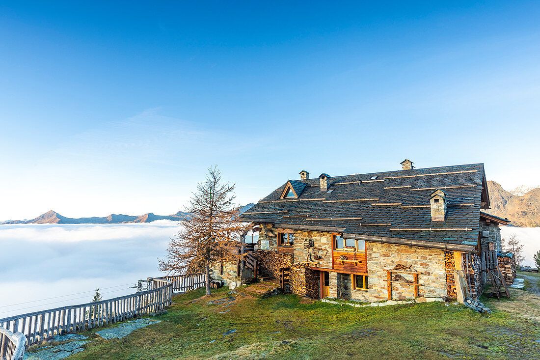 Motta mountain hut at sunrise with fog that covers the valley, Valmalenco, Valtellina, Lombardy, Italy, Europe