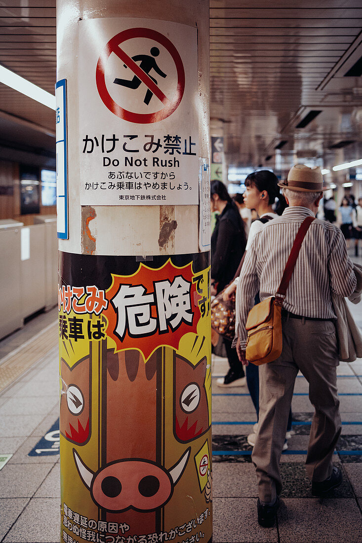 Pensioners on the subway with warning notices in the foreground, Toyko, Japan