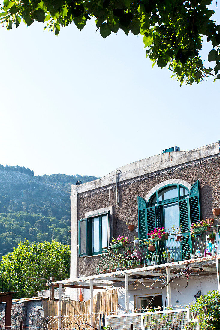 Balkon und Fensterläden eines Hauses auf einer Kulisse mit Bergen in Capri, Italien