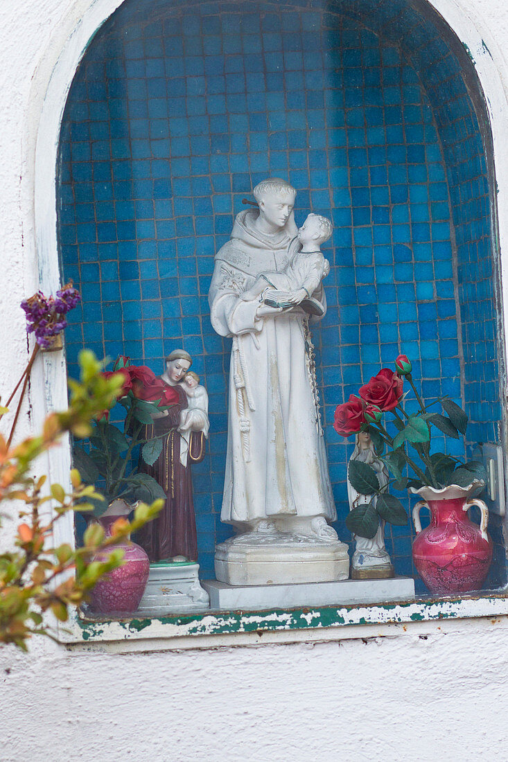 Religiöse Statue und Blumen in einer Wandnische in Capri, Italien