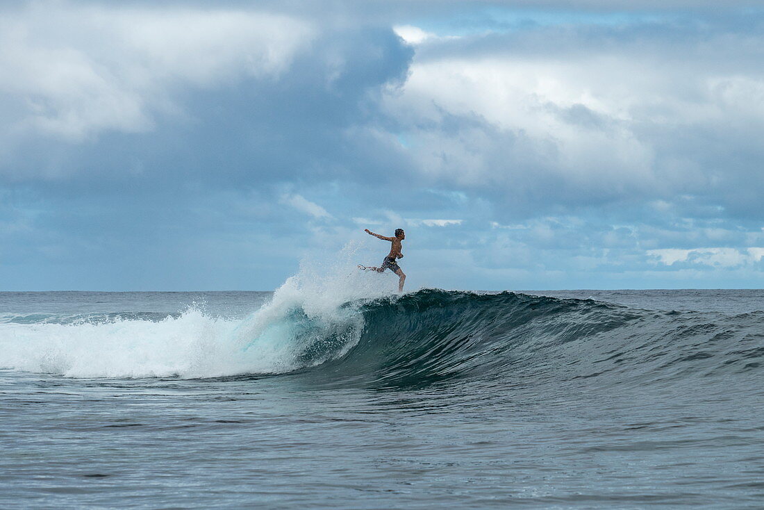 Ein Surfer scheint auf dem Wasser laufen zu können – auf einer brechenden Welle im Surfgebiet Teahupoo, Tahiti Iti, Tahiti, Windward Islands, Französisch-Polynesien, Südpazifik