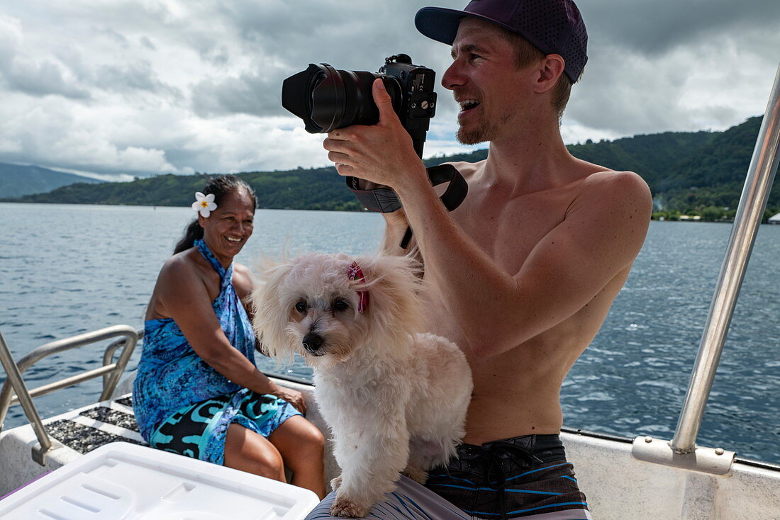 Photographer and small dog during boat excursion, Tahiti Iti, Tahiti, Windward Islands, French Polynesia, South Pacific