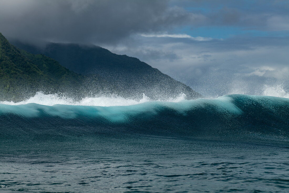 Breaking wave in the Teahupoo surfing area in front of a mountain backdrop, Tahiti Iti, Tahiti, Windward Islands, French Polynesia, South Pacific