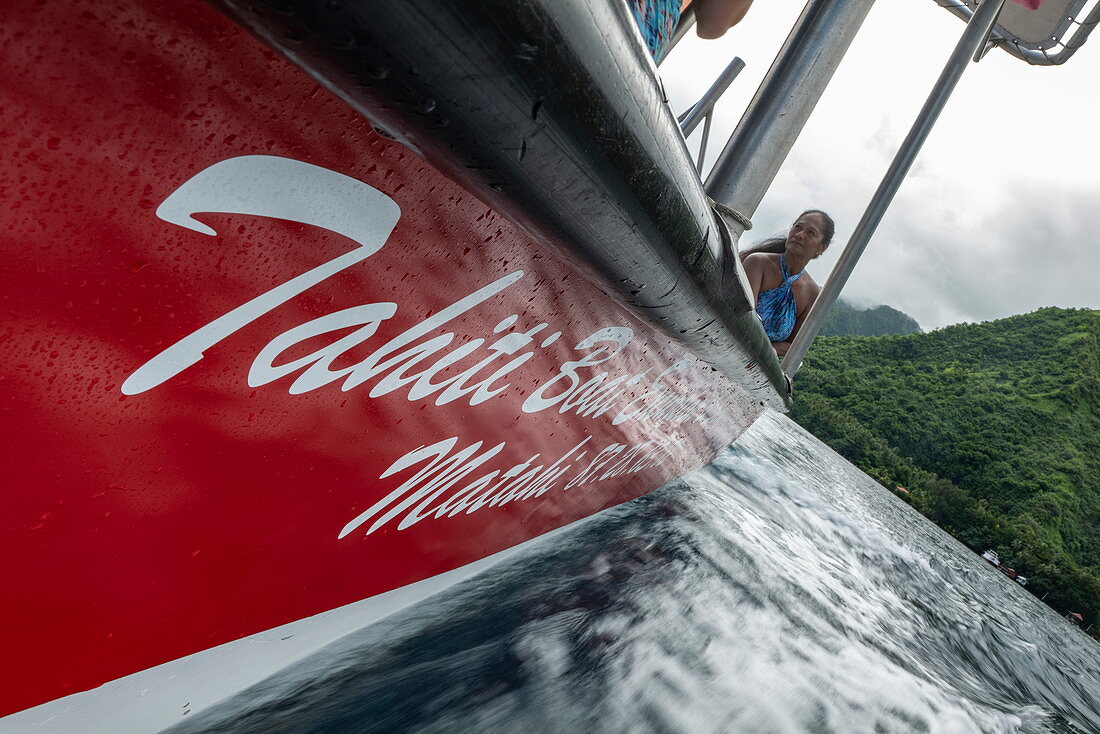 Low view of the side of a red tour boat with water spray, Tahiti Iti, Tahiti, Windward Islands, French Polynesia, South Pacific