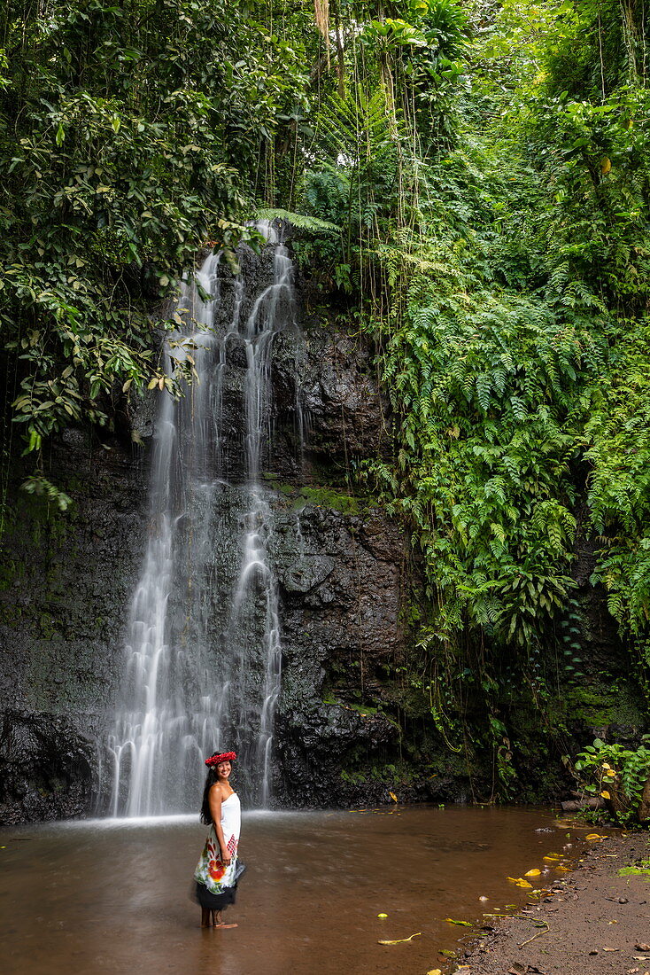 Beautiful young Tahitian woman in front of waterfall in 'The Water Gardens of Vaipahi', Teva I Uta, Tahiti, Windward Islands, French Polynesia, South Pacific
