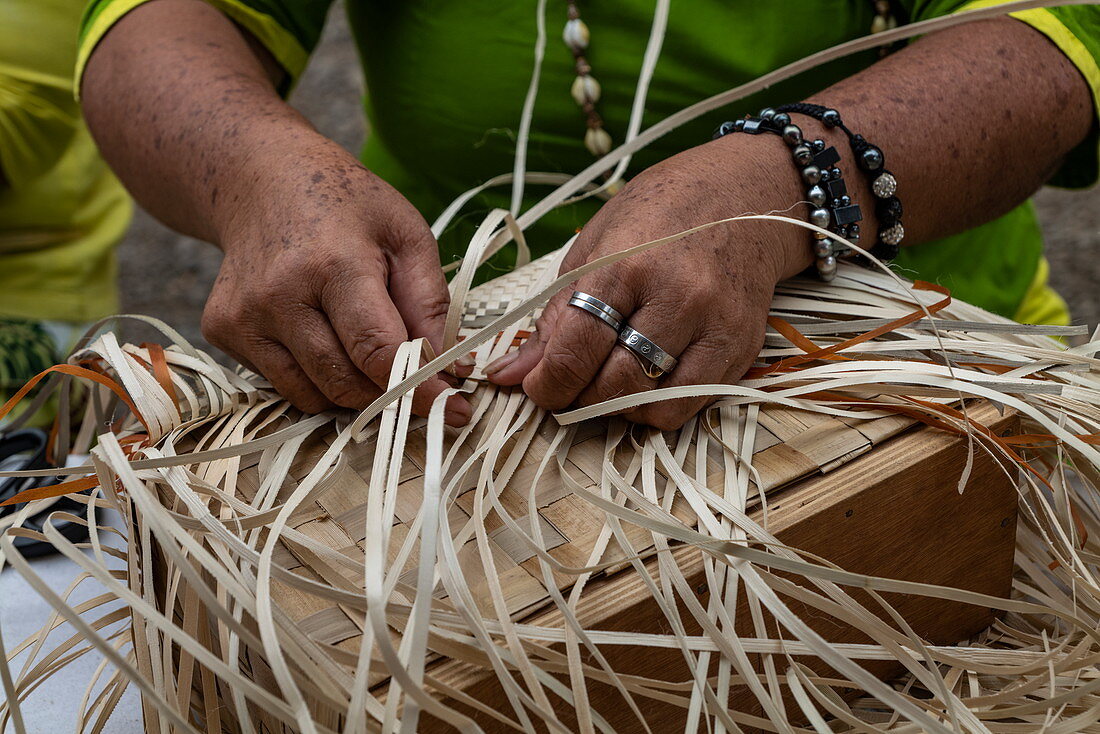 Detail von Händen einer Frau, die auf traditionelle Art bei einem Kulturfestival eine Tasche aus Pandanusfasern webt, Papeete, Tahiti, Windward Islands, Französisch-Polynesien, Südpazifik