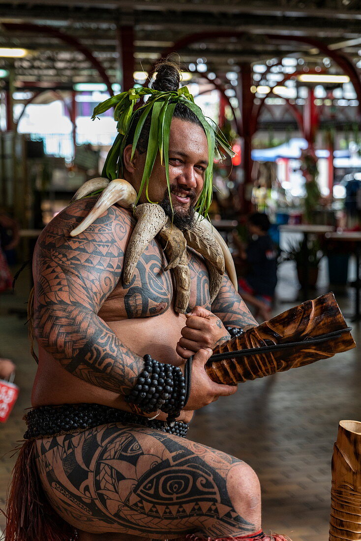 Ein tahitianischer "Krieger" mit Tätowierungen heißt die Besucher in der Markthalle "Marché Papeete" willkommen, Papeete, Tahiti, Windward Islands, Französisch-Polynesien, Südpazifik