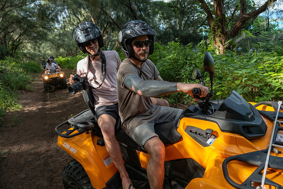 Menschen beim Ausflug mit Quad Geländefahrzeug auf unbefestigter Straße durch üppige Bergvegetation, Bora Bora, Leeward Islands, Französisch-Polynesien, Südpazifik