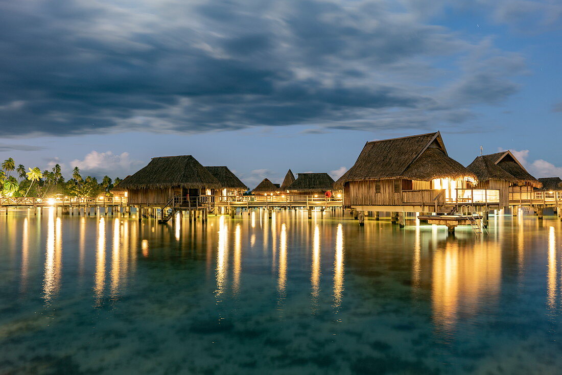 Overwater bungalows of the Sofitel Ia Ora Beach Resort in the Moorea Lagoon at dusk, Moorea, Windward Islands, French Polynesia, South Pacific