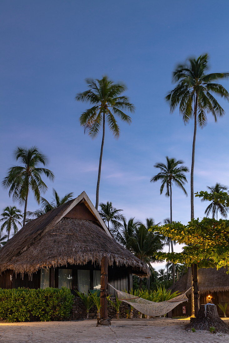 Hammock on the beach and bungalows of the Sofitel Ia Ora Beach Resort at daybreak, Moorea, Windward Islands, French Polynesia, South Pacific