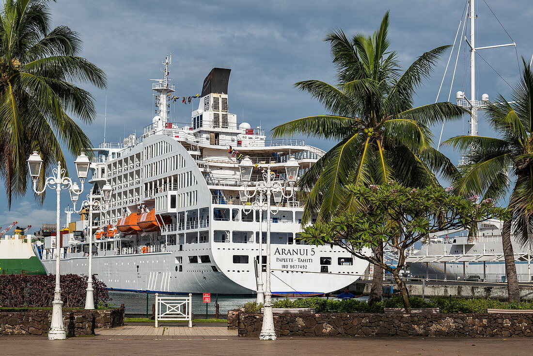 Palmen an der Hafenpromenade und Passagierfrachtschiff Aranui 5 (Aranui Cruises) am Pier, Papeete, Tahiti, Windward Islands, Französisch-Polynesien, Südpazifik