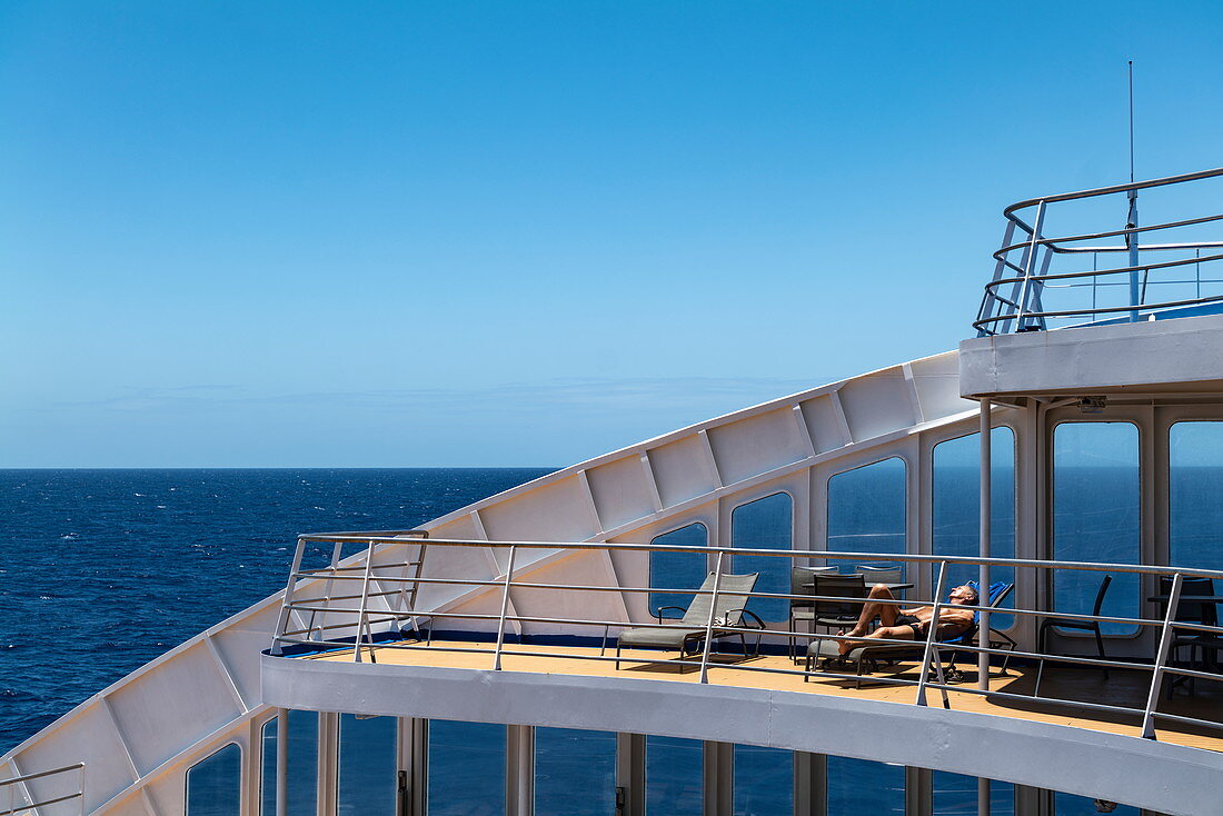 Man entspannt sich auf dem Sonnendeck von Passagierfrachtschiff Aranui 5 (Aranui Cruises), auf See zwischen den Tuamotu-Inseln und den Marquesas-Inseln, Französisch-Polynesien, Südpazifik
