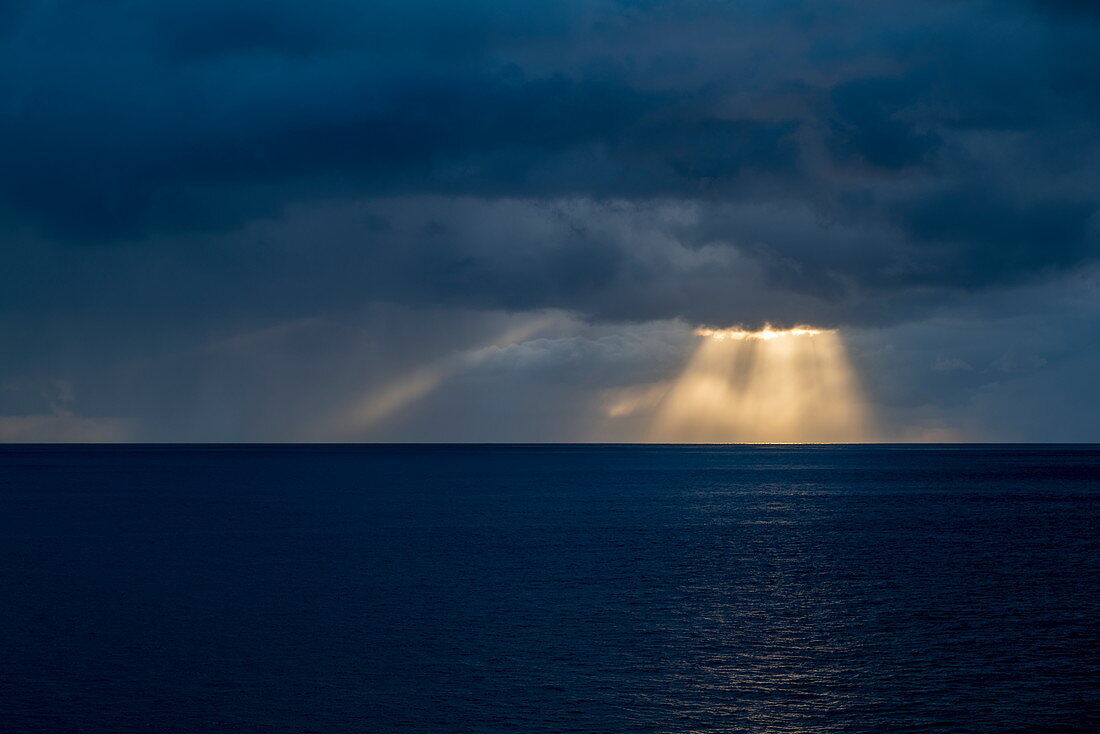 Sonnenstrahlen brechen durch Gewitterwolken nahe Fatu Hiva, Marquesas-Inseln, Französisch-Polynesien, Südpazifik
