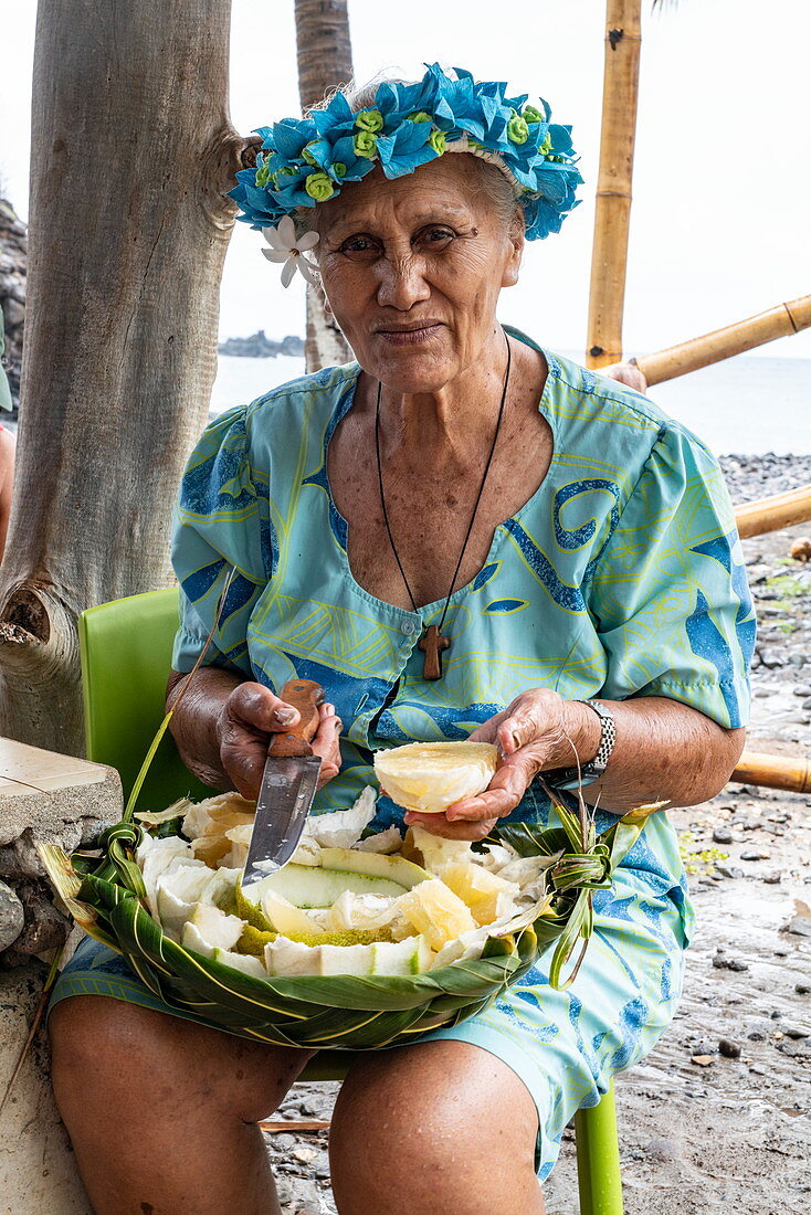 Ältere Frau bietet tropische Fruchtstücke an, Hokatu, Ua Huka, Marquesas-Inseln, Französisch-Polynesien, Südpazifik