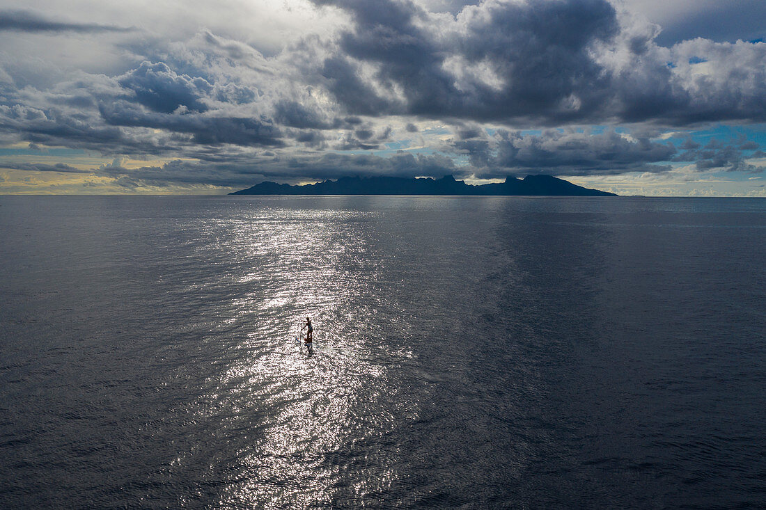 Luftaufnahme von SUP Stand Up Paddler bei Sonnenuntergang mit Insel Moorea in der Ferne, Nuuroa, Tahiti, Windward Islands, Französisch-Polynesien, Südpazifik