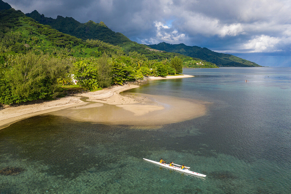 Aerial view of beach and coastline and outrigger racing canoe in Moorea Lagoon, Avamotu, Moorea, Windward Islands, French Polynesia, South Pacific