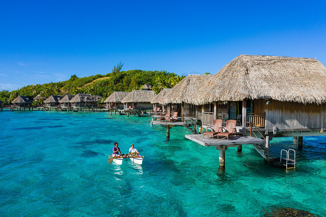 Aerial view of how breakfast is brought by pirogue outrigger canoe to an overwater bungalow of the Sofitel Bora Bora Private Island Resort in the Bora Bora Lagoon, Bora Bora, Leeward Islands, French Polynesia, South Pacific