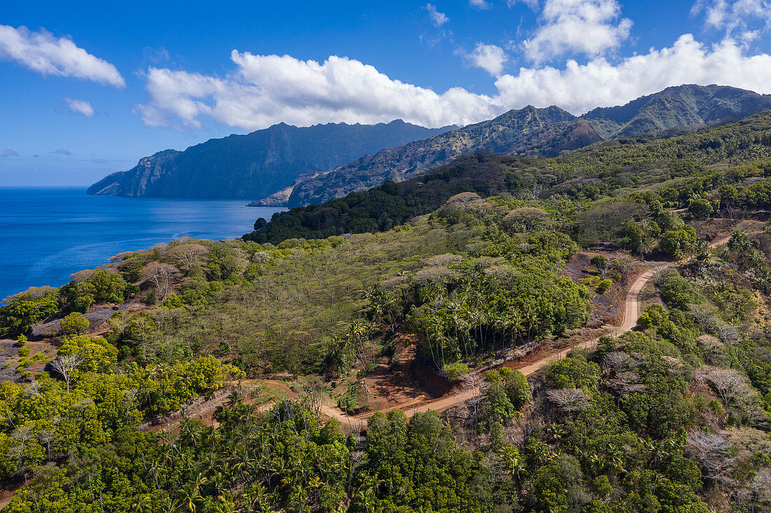 Luftaufnahme von unbefestigter Straße am Hang mit Bergen und Küste dahinter, Omoa, Fatu Hiva, Marquesas-Inseln, Französisch-Polynesien, Südpazifik