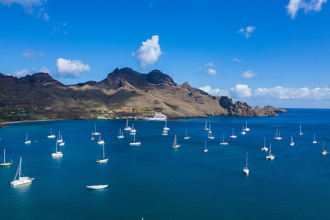 Luftaufnahme von Segelbooten vor Anker und Passagierfrachter Aranui 5 (Aranui Cruises) am Pier in der Ferne, Taiohae, Nuku Hiva, Marquesas-Inseln, Französisch-Polynesien, Südpazifik