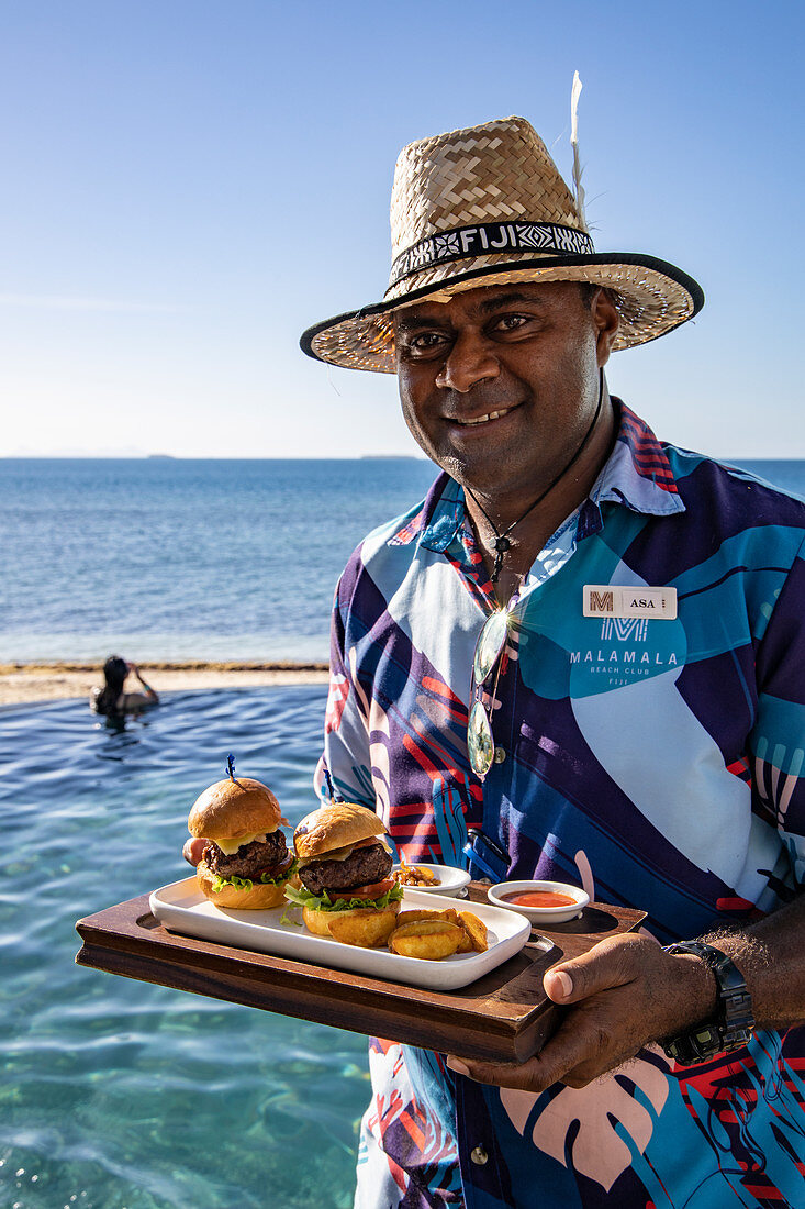 Friendly waiter serves delicious burgers at Malamala Island Beach Club, Mala Mala Island, Mamanuca Group, Fiji Islands, South Pacific