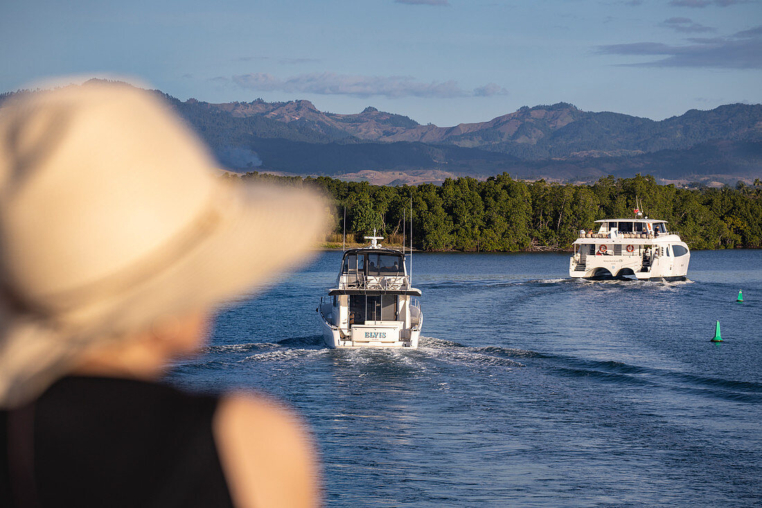 Boote kehren am späten Nachmittag in die Port Denarau Marina zurück mit Frau die einen Sonnenhut trägt im Vordergrund, Port Denarau, nahe Nadi, Viti Levu, Fidschi-Inseln, Südpazifik