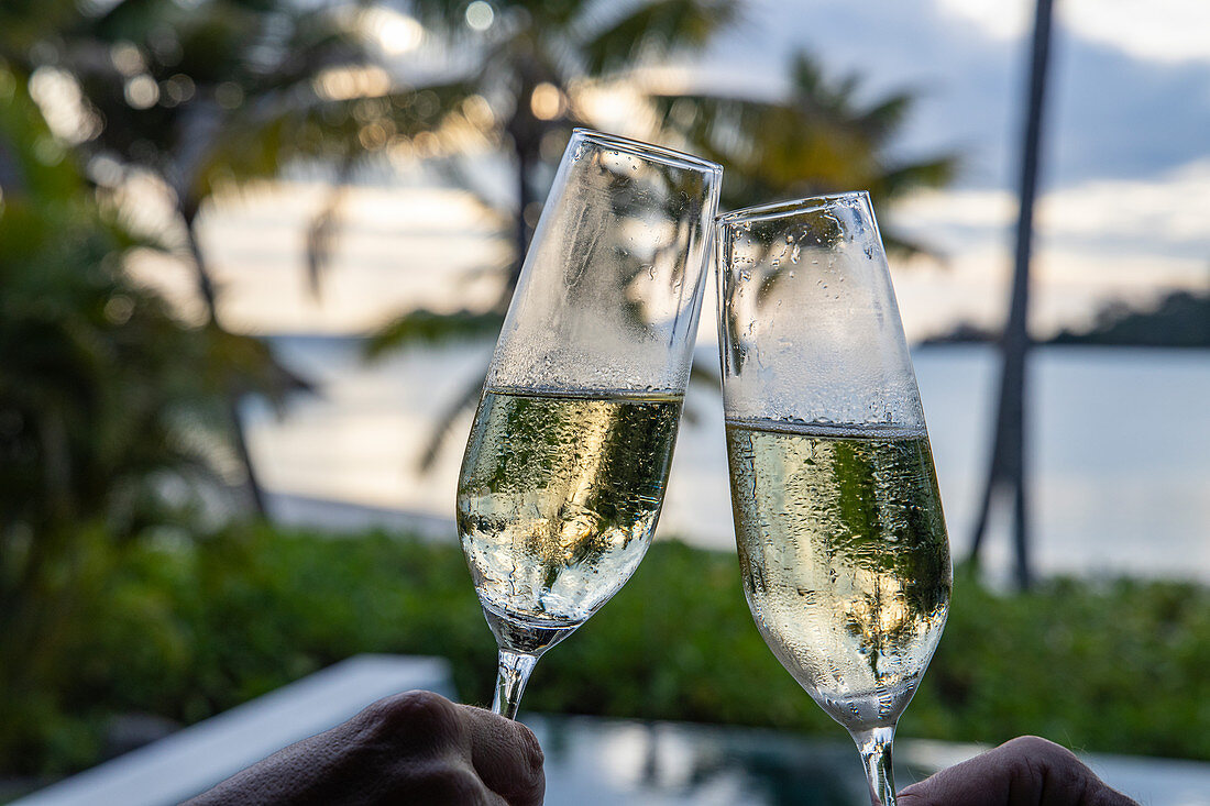 Anstoßen mit zwei Gläsern Champagner in einer Residenz Villa im Six Senses Fiji Resort, Malolo Island, Mamanuca Group, Fidschi-Inseln, Südpazifik