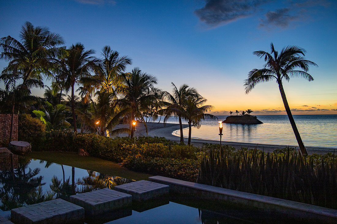 Tiki Fackeln und privater Swimming Pool einer Residence Villa Unterkunft im Six Senses Fiji Resort in der Abenddämmerung, Malolo Island, Mamanuca Group, Fidschi-Inseln, Südpazifik