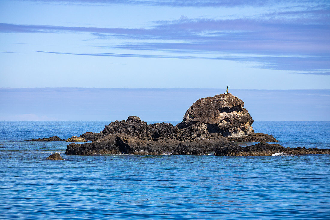 A Fijian stands on a rock and welcomes passengers on the Yasawa Flyer II (South Sea Cruises) catamaran as it approaches the Yasawa Archipelago the traditional way, Kuata Island, Yasawa Group, Fiji Islands, South Pacific