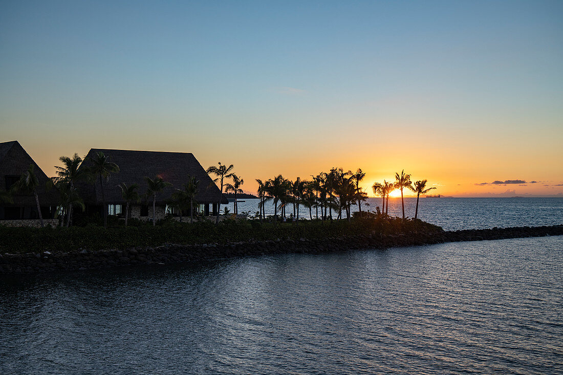 Silhouette von Villen eines Resort und Kokospalmen am Eingang zur Port Denarau Marina bei Sonnenuntergang, Port Denarau, nahe Nadi, Viti Levu, Fidschi-Inseln, Südpazifik