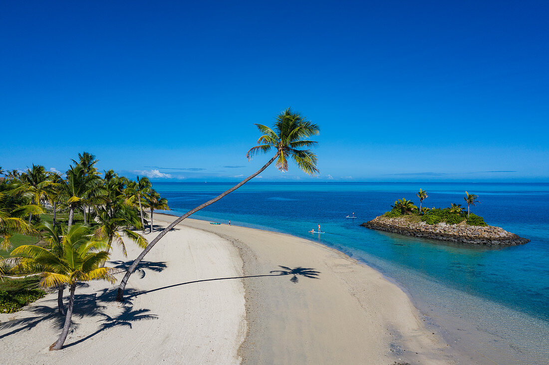 Luftaufnahme einer Residence Villa Unterkunft im Six Senses Fiji Resort mit Kokospalmen, Strand und Familie die Wassersport Aktivitäten neben kleiner vorgelagerter  Insel genießt, Malolo Island , Mamanuca Group, Fidschi-Inseln, Südpazifik