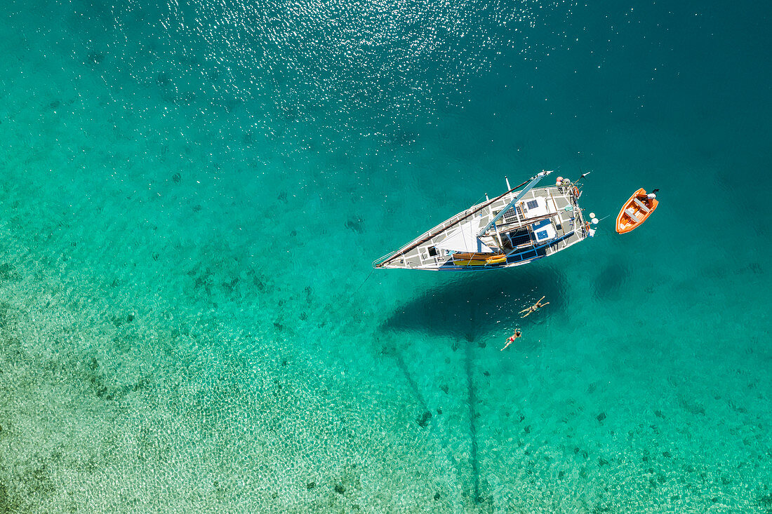 Aerial view of couple swimming from sandbar to their sailboat, near Malolo Island, Mamanuca Group, Fiji Islands, South Pacific