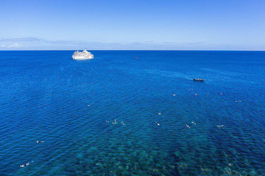 Luftaufnahme von Menschen die schnorcheln und Wassersport entlang Korallenriff genießen mit Kreuzfahrtschiff MV Reef Endeavour (Captain Cook Cruises Fiji) in der Ferne, Yaqeta, Yangetta Island, Yasawa Group, Fidschi-Inseln, Südpazifik