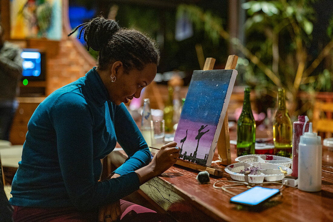 Woman paints picture during painting class event at Heaven Restaurant, Kigali, Kigali Province, Rwanda, Africa