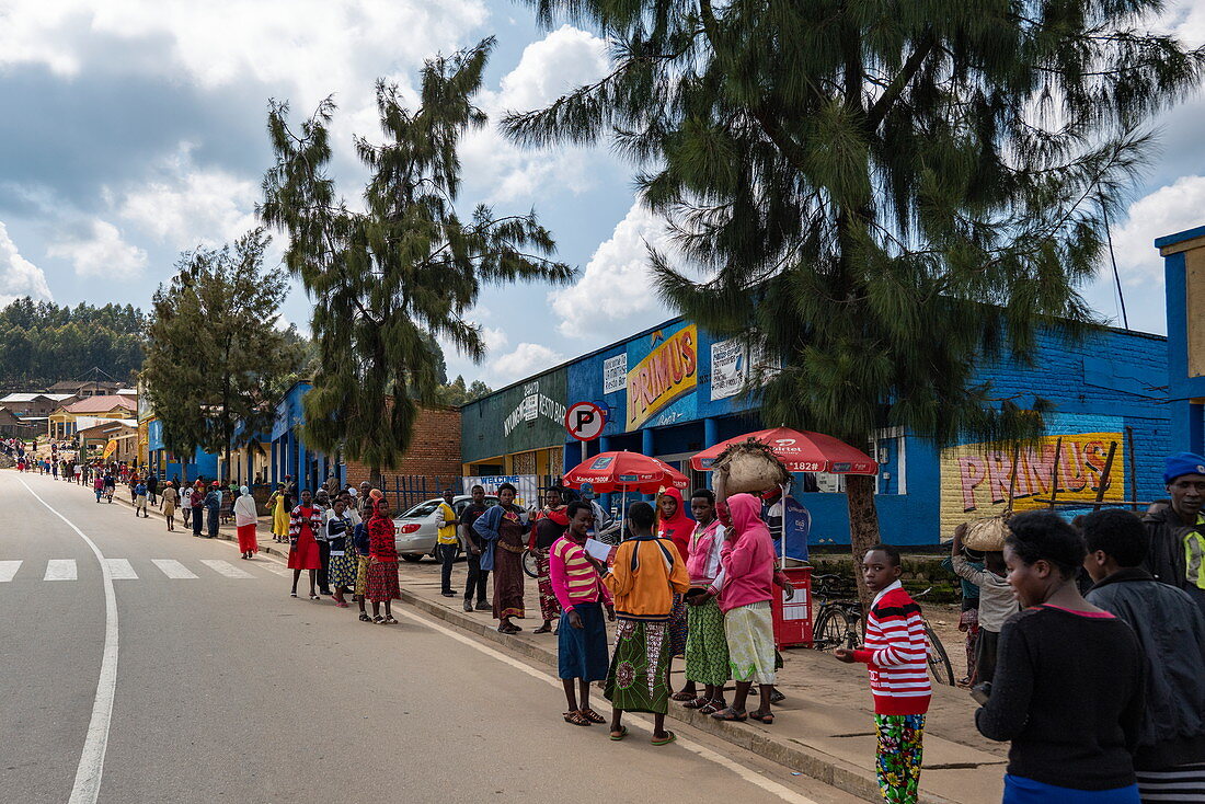 Straßenszene mit vielen Menschen die bunte Kleidung tragen, nahe Mudasomwa, Southern Province, Ruanda, Afrika