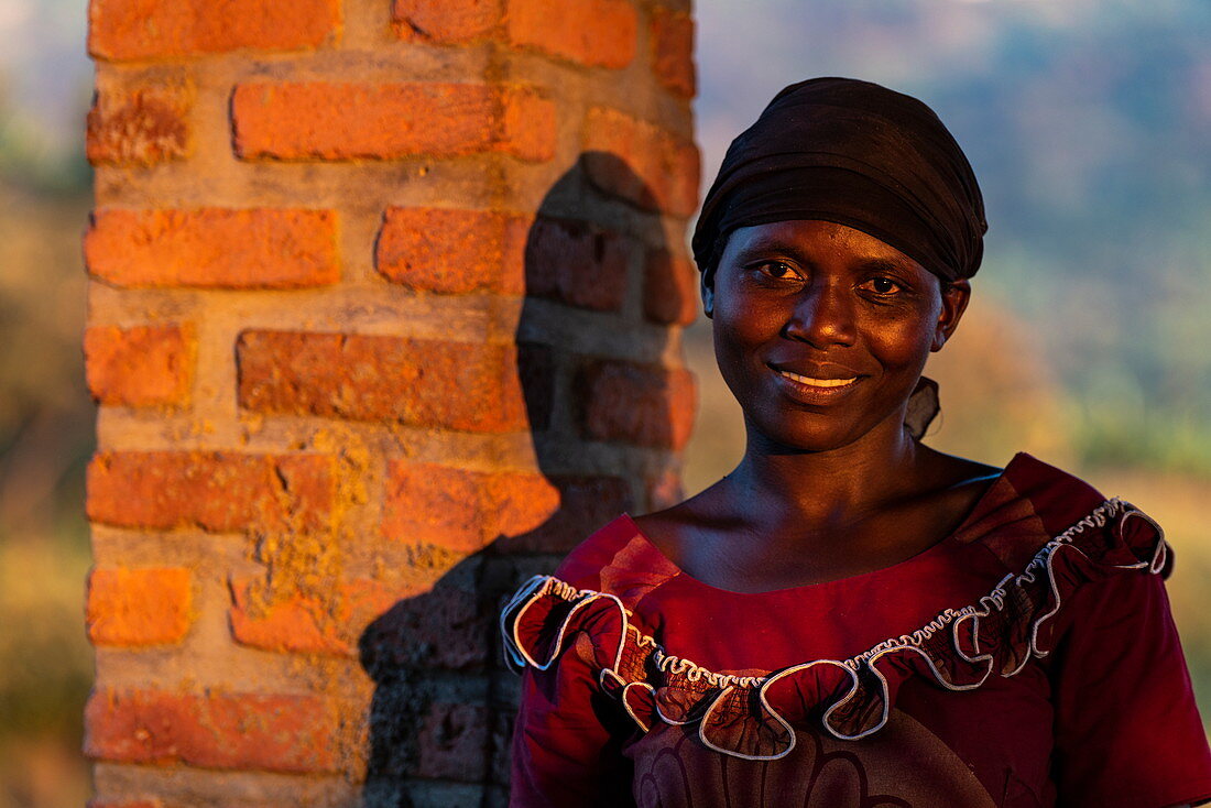 Portrait of a smiling Rwandan woman in late afternoon light, Kinunu, Western Province, Rwanda, Africa