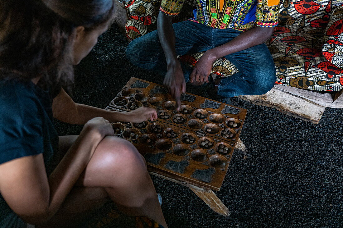 Zwei Menschen spielen das traditionelle Igisoro Brettspiel in der Lounge vom Paradis Malahide Hotel, Gisenyi, Western Province, Ruanda, Afrika