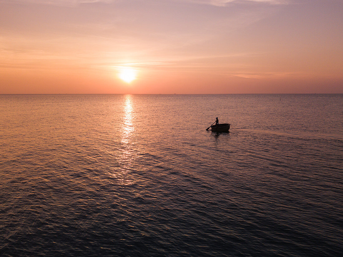 Aerial view silhouette of fisherman in traditional round boat at sunset, Ong Lang, Phu Quoc Island, Kien Giang, Vietnam, Asia
