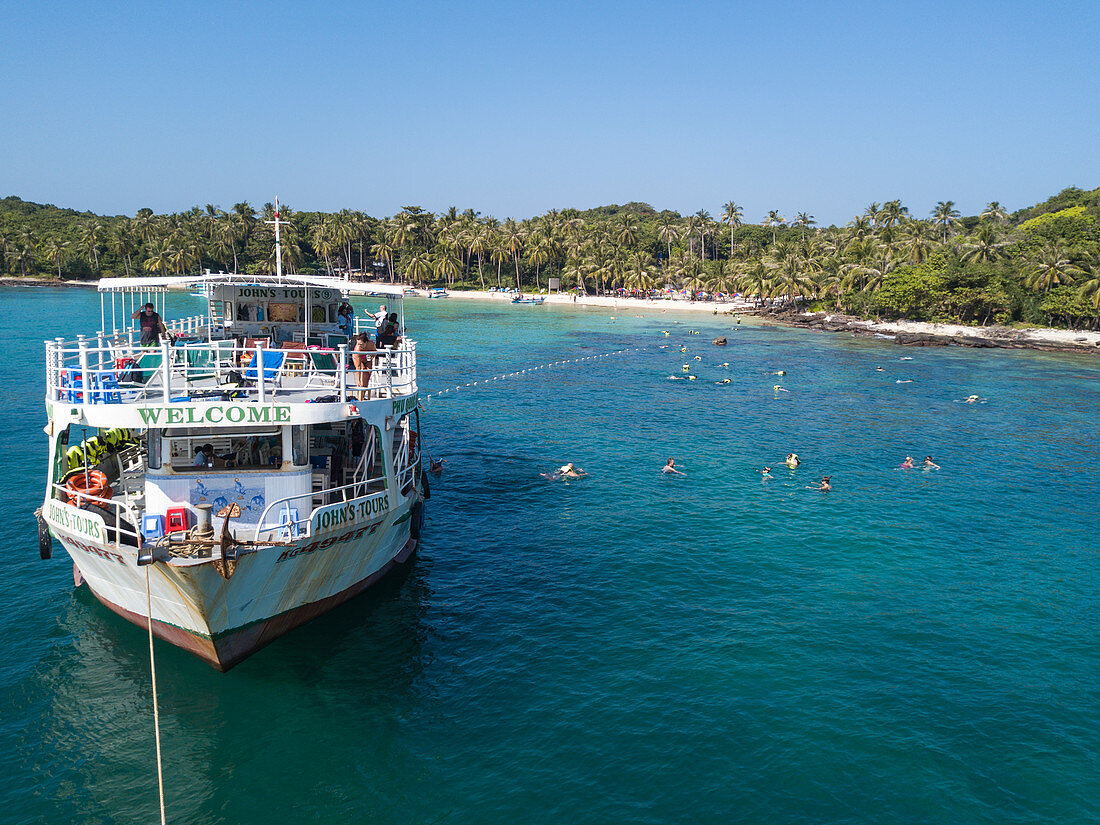 Luftaufnahme von John's Tours Nr. 9 Ausflugboot und Touristen die in klarem Wasser nahe Strand mit Kokospalmen schnorcheln, May Rut Island, nahe Insel Phu Quoc, Kien Giang, Vietnam, Asien