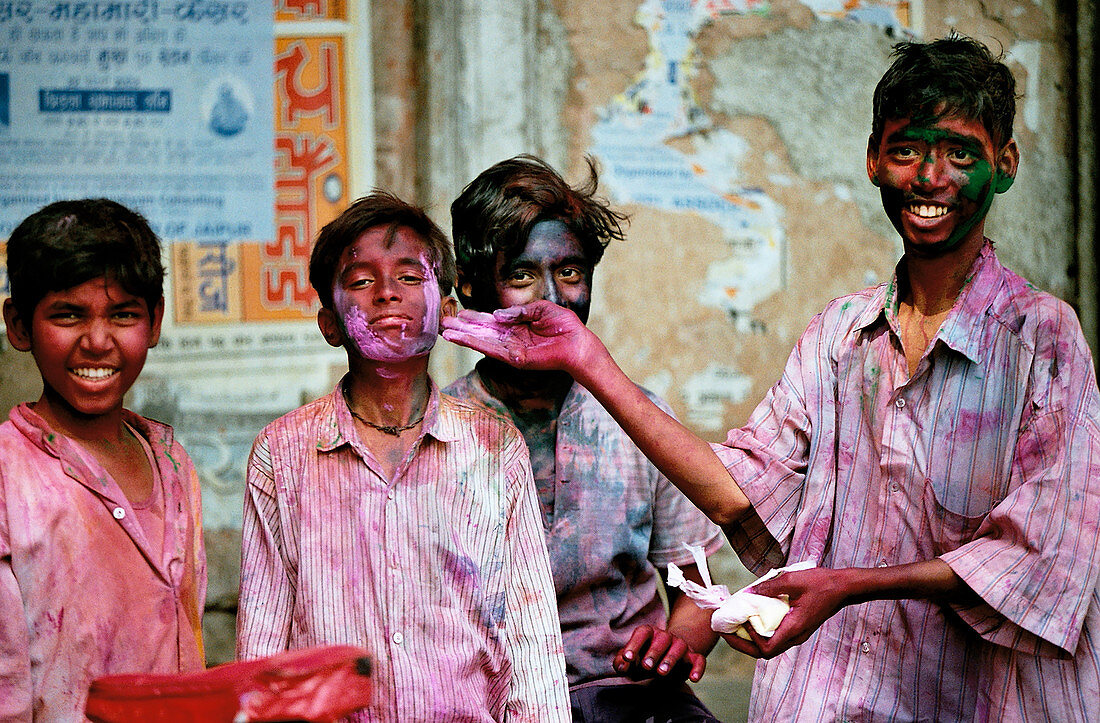 Indische Jungen feiern Holi mit bunten Farben in den Gesichtern und auf ihren Kleidern. Jaipur, Indien