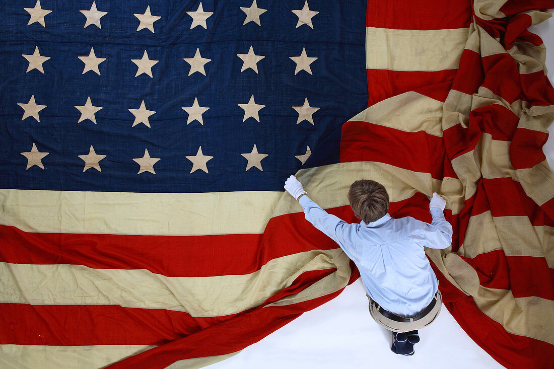 Ein Mann, der eine riesige amerikanische Flagge ausklappt. Texas, USA