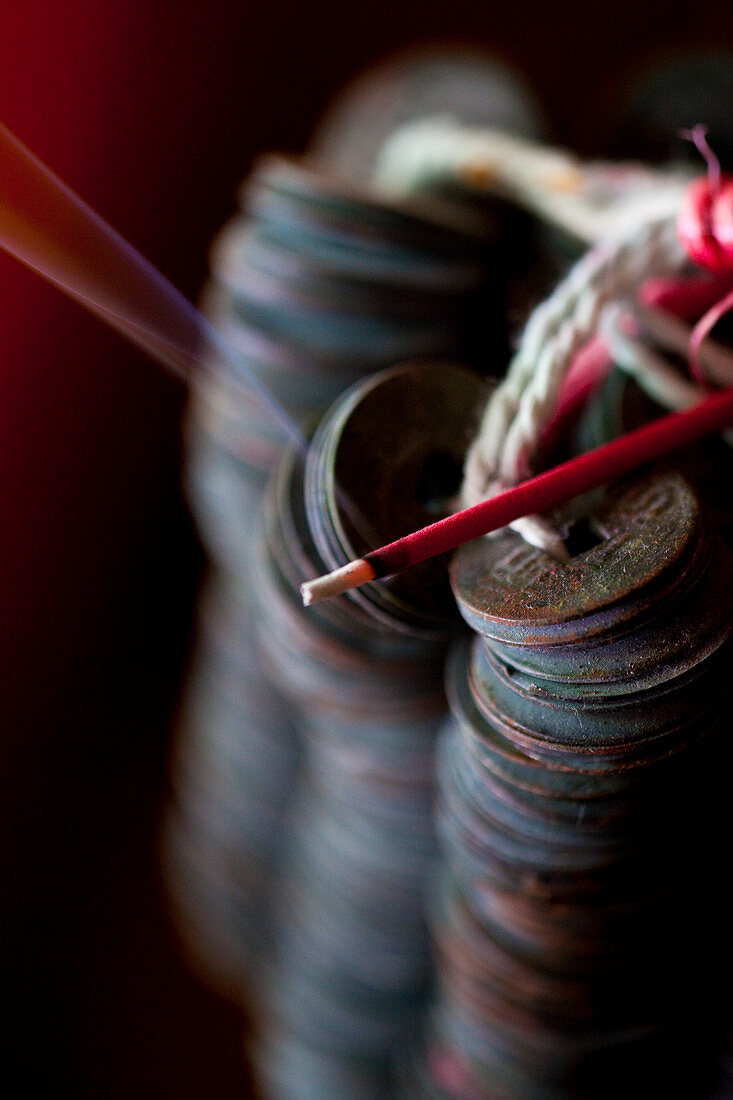 Ceremonial  coins with a burning incense  stick. Shot in Bali.