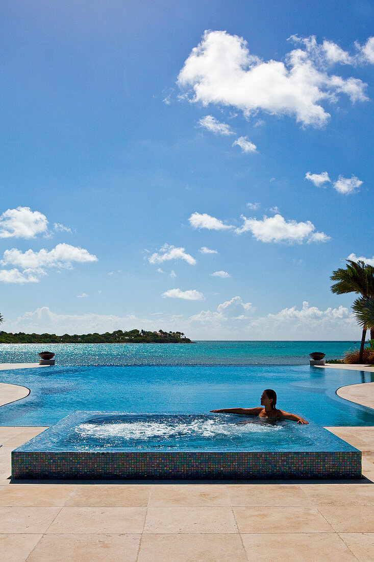 Frau in einem Whirlpool neben einem Infinity-Pool. Antigua, Westindische Inseln